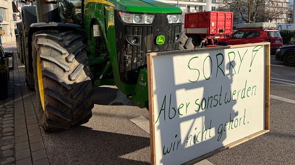 Traktor mit einem Schild vorn "Sorry, aber sonst werden wir nicht gehört".