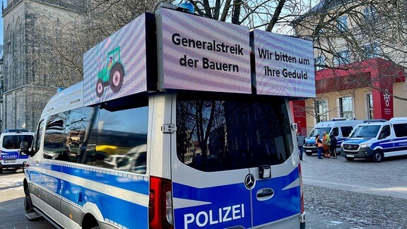 Polizeiauto begleitet Demo von protestierenden Bauern.