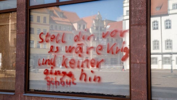 Eine Scheibe in Wittenberg mit Graffito: "Stell dir vor, es ist Krieg, und keiner schaut hin."
