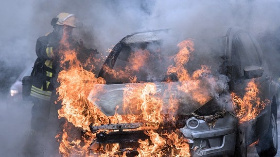 Die Feuerwehr löscht ein brennendes Auto.