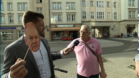 MDR Reporter Stefan Bernschein mit Olaf-Scholz-Maske im Gespräch mit einem Passanten