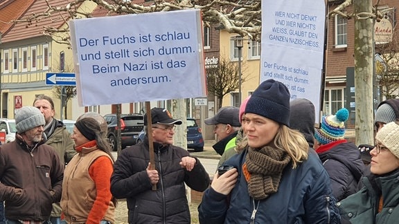 Mehrere Menschen demonstrieren, auf einem Schild steht: "Der Fuchs ist schlau und stellt sich dumm, beim Nazi ist das andersrum."