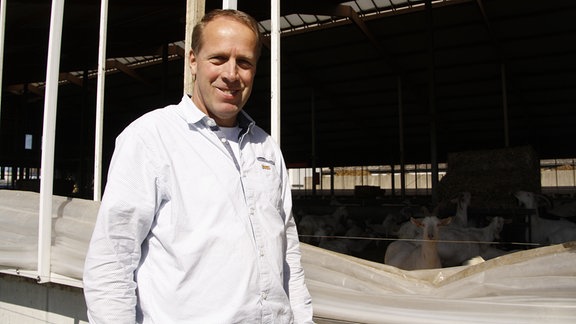 Landwirt Jan de Vries steht vor seinem offenen Stall mit Ziegen