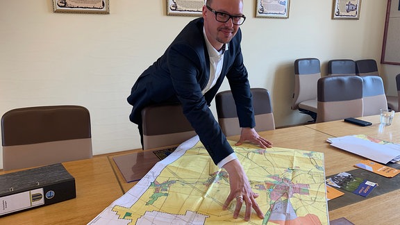 Zörbigs Bürgermeister Matthias Egert beugt sich über eine Karte mit Plänen zum Ausbau der Windkraft.