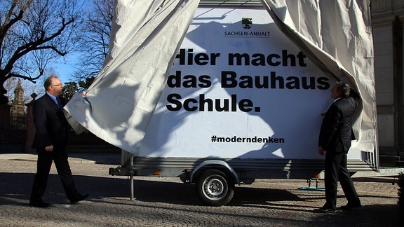 Ministerpräsident Reiner Haseloff (l.) enthüllt das neue Bauhaus-Plakat