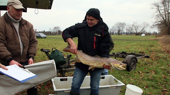 Robert Frenzel vom Institut für Binnenfischerei Potsdam und Olaf Saar vom Anglerverein Zerbst (v.l.) mit einem Lachs