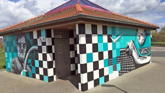 Blaues Graffiti mit Rennfahrer an einem Toilettenhäuschen