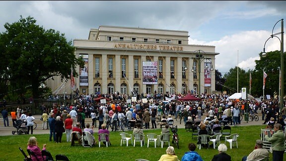 Auf der Wiese vor dem Theaterhaus in Dessau machen viele Menschen Spektakel.