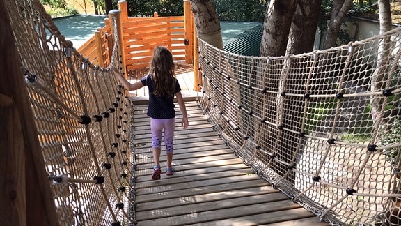 Ein Mädchen läuft eine Hängebrücke nach unten.