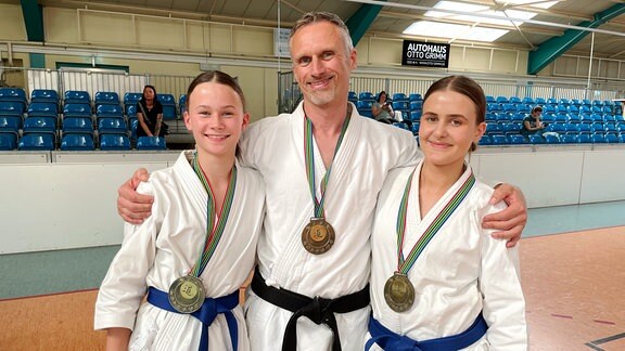 Melina, Thomas und Tessa Gelbrich in Karate-Kleidung mit Medaillen um den Hals.