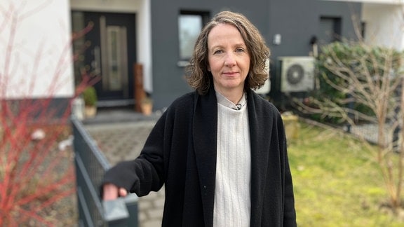 Anke Maiwald steht am Tor ihres Grundstücks im Wohngebiet "Zur Luther Linde" in Muldenstein und blickt in die Kamera.