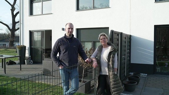 Jan Kohlwes und Claudia Granitzki sind direkte Nachbarn im Wohngebiet "Zur Luther Linde". An der Grenze zwischen ihren Grundstücken stehen sie am Gartenzaun und blicken in die Kamera.