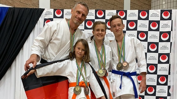 Familie Gelbrich mit Medaillen auf dem Podest bei den Karate-Weltmeisterschaften in Südafrika 2019.