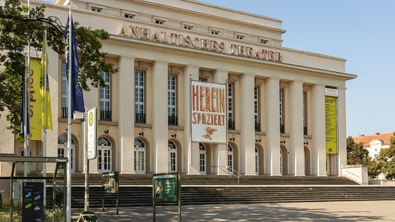Blick auf das Anhaltisches Theater in Dessau. An der Fassade hängt ein Plakat, auf dem steht: "Herein spaziert".
