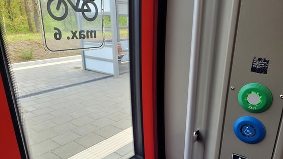 Foto aus der Zugtür auf den Bahnhof Meinsdorf. Im Zug ist ein Knopf für Rollstuhlfahrer.
