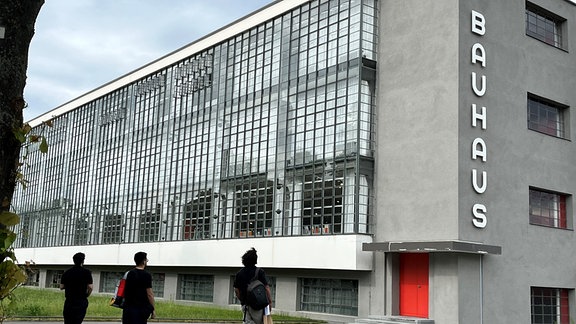 Drei Architekturstudenten bestaunen das Bauhaus Dessau und seinen wieder angebrachten Schriftzug.