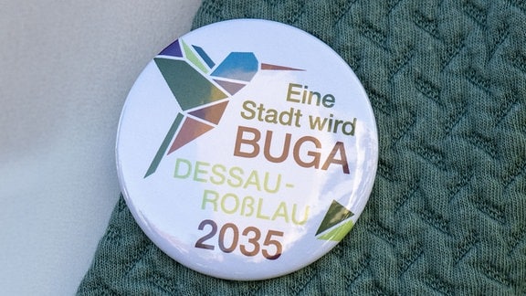 «Eine Stadt wird BUGA - Dessau-Roßlau 2035» steht auf dem Button einer Teilnehmerin während des Besuchs von Jury-Mitgliedern der Deutschen Bundesgartenschau-Gesellschaft (dbg) in Dessau-Roßlau.