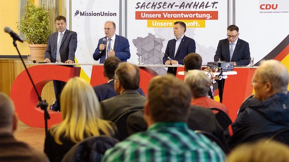CDU-Politiker stehen vor Publikum an einem Tisch.