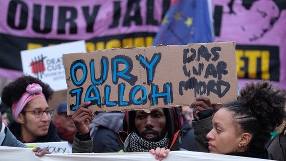 Teilnehmer einer Demonstration gehen mit einem Transparent mit der Aufschrift "Oury Jalloh das war Mord" auf der Straße.