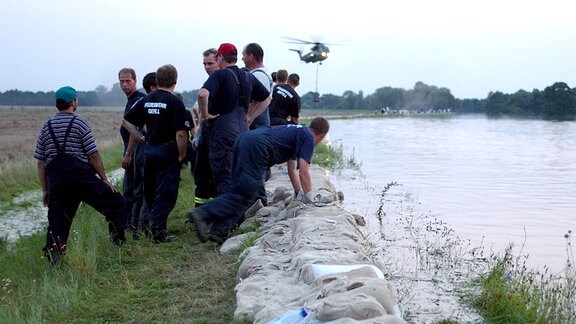 Nachbarschaftshilfe - Feuerwehrleute aus Gefell bauen einen Damm aus Sandsäcken an der Mulde im Einsatzgebiet Mildensee