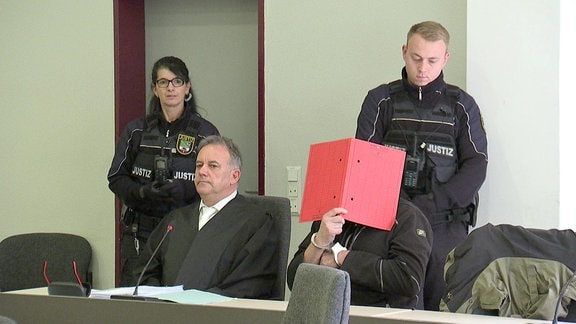 Ein Mann hinter einem roten Ordner im Landgericht Dessau-Roßlau