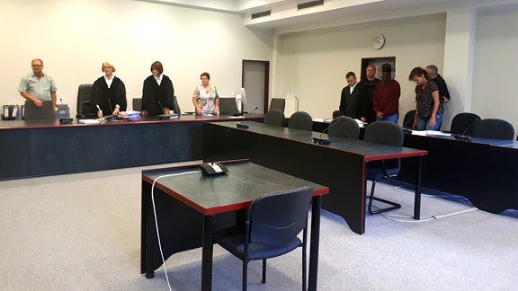Mehrere Personen stehen im Gerichtssaal des Landgerichts Dessau