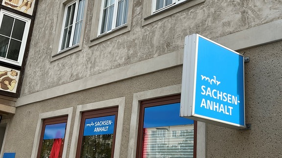 Vor dem Regionalstudio Dessau des MDR weisen blaue Schilder und Aufkleber auf das Sendestudio hin.