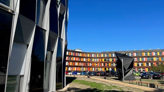 Ein modernes schwarz-weißes geometrisch gestaltetes Gebäude und ein in Rottönen gestaltetes modernes Gebäude