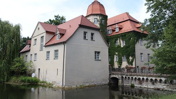 Blick auf das Wasserschloss von Groß Paschleben mit Wassergraben und Steinbrücke