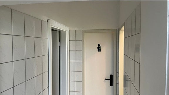 Blick in weiß gefliesten Toiletten- und Umkleidebereich