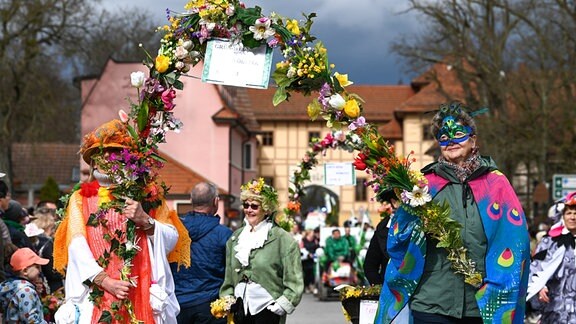 Teilnehmerinnen des Festumzugs zum Frühlingserwachen gehen mit einem Blumenbogen. Die Veranstaltung ist der traditionelle Beginn der Tourismussaison im Gartenreich Dessau-Wörlitz.