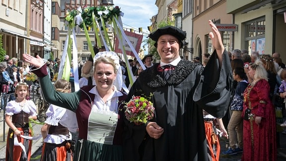 Das Brautpaar Martin Luther und Katharina von Bora, dargestellt von Carolin und Oliver Koschmieder winken den Zuschauern am Rand des Festumzuges. 