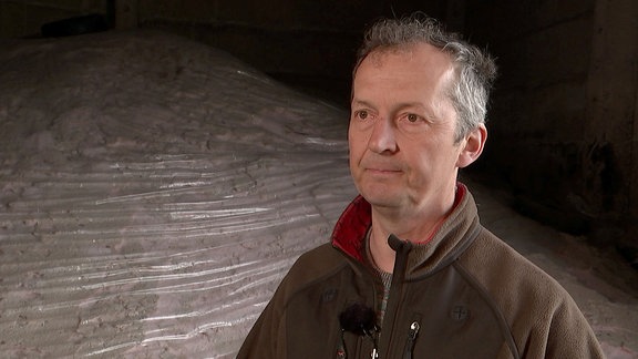 Landwirt Stefan Gutzmer steht vor einem Berg aus Stickstoff-Dünger.