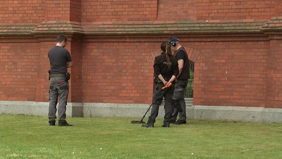 Kriminalbeamte untersuchen mit Metalldetektoren den Rasen vor dem Neuen Rathaus in Wittenberg