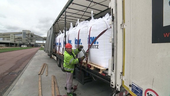 Riesige befüllte Säcken mit der Aufschrift SKW Piesteritz werden auf einen Lkw verladen 