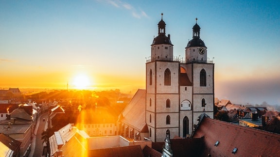 Blick über die Innenstadt Wittenbergs bei aufgehender Sonne neben der Stadtkirche