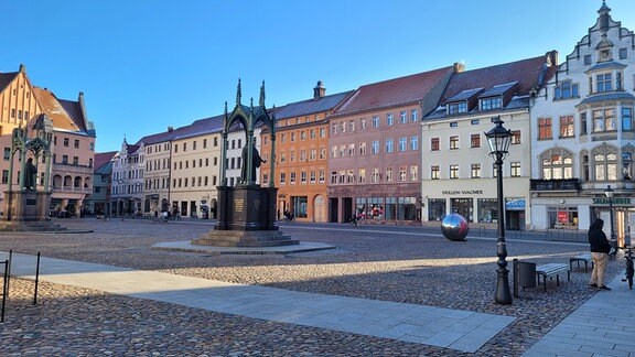 Lutherdenkmal auf dem Wittenberger Marktplatz, drumherum zahlreiche alte Häuser.