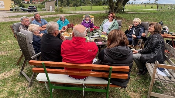 Menschen sitzen auf Bänken bei einem Picknick