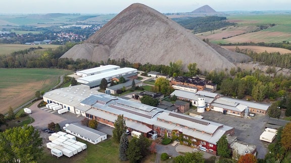 Luftbild eines alten Fabrikgeländes vor einem Hügel.