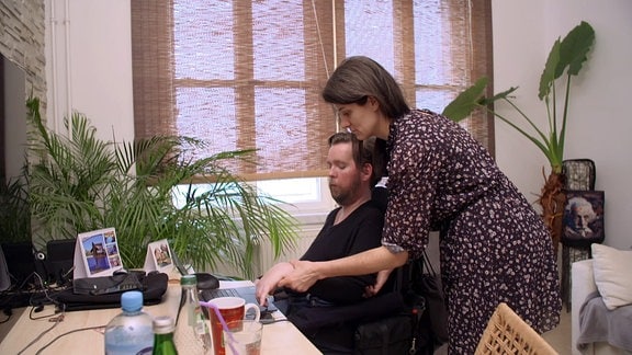 Eine Frau hilft einem Mann im Rollstuhl