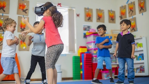 Spielende Kinder im Kindergarten, ein Mädchen trägt eine VR-Brille