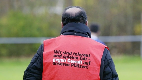 Ein Ordner trägt eine Sicherheitsweste mit der Aufschrift Gegen Gewalt und für Toleranz am Spielfeldrand.