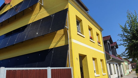 Eine große PV-Anlage an einem gelben Haus.
