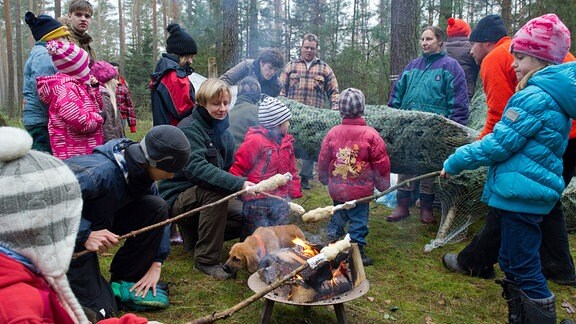Kinder stehen mit Knüppelkuchen an einem Lagerfeuer