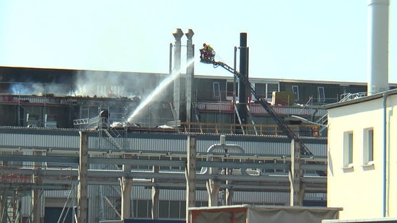 Ein Feuerwehrmann auf einer Drehleiter löscht einen Großbrand am Aluminiumwerk in Nachterstedt.