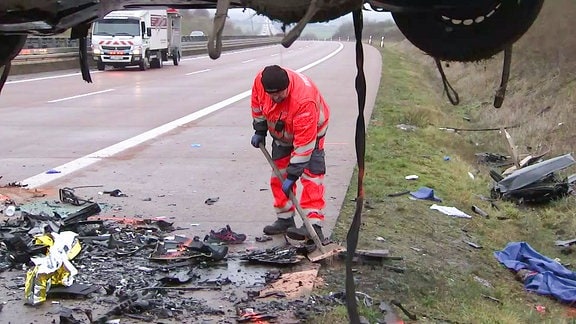 Autobahnmeisterei-Mitarbeiter beseitigt Schäden an einem Unfallort