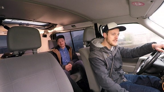Zwei junge Männer sitzen in einem VW-Bus