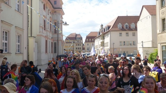 Eine große Menschenmenge läuft mit Regenbogenfahnen und Transparenten beim CSD 2023 durch Weißenfels.