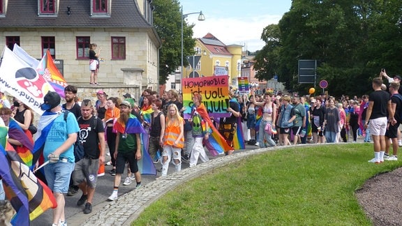 Eine große Menschenmenge läuft mit Regenbogenfahnen und Transparenten beim CSD 2023 durch Weißenfels.