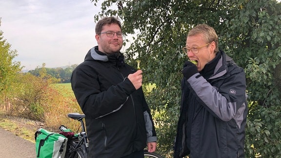 Leonard Schubert und André Plaul haben auf dem Radweg angehalten und essen Äpfel.